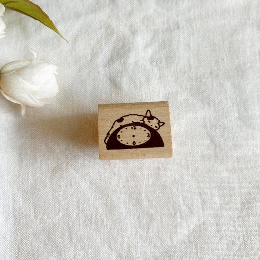 Pottering Cat rubber stamp titled 'Clock,' featuring a cute cat sleeping on top of a clock, Japanese stationery perfect for adding a whimsical time-themed touch to planners, journals, and crafts