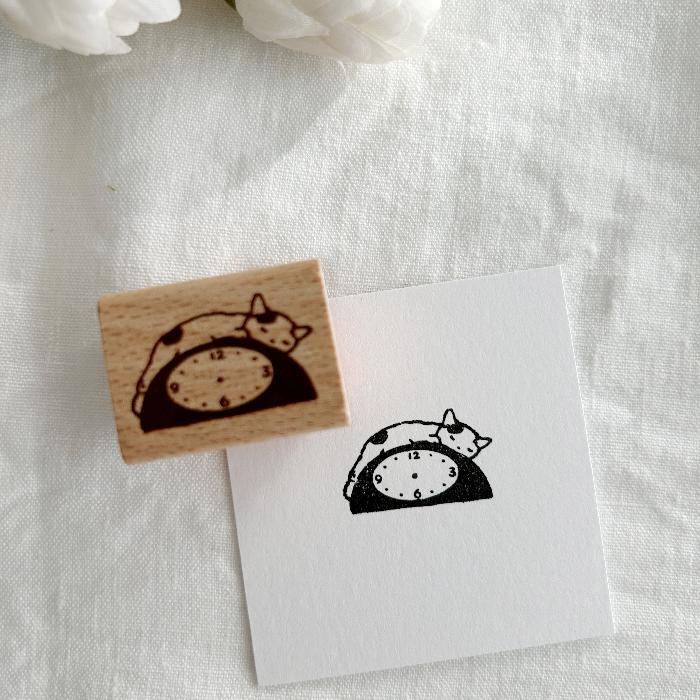 Pottering Cat rubber stamp titled 'Clock,' featuring a cute cat sleeping on top of a clock, Japanese stationery perfect for adding a whimsical time-themed touch to planners, journals, and crafts