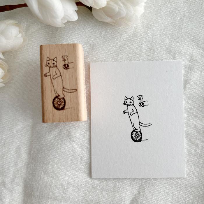 Pottering Cat rubber stamp titled 'Unicycle,' featuring a playful cat riding a unicycle, Japanese stationery perfect for adding a playful and adventurous touch to planners, journals, and crafts.