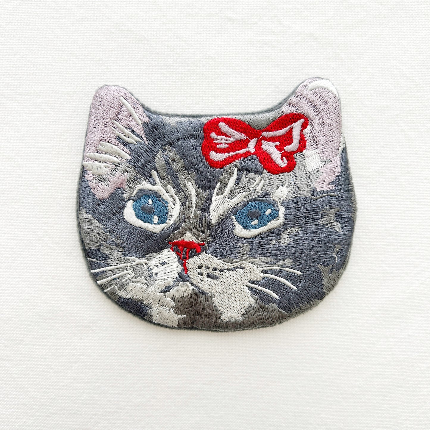 Embroidered pouch of a cat's face with a red bow