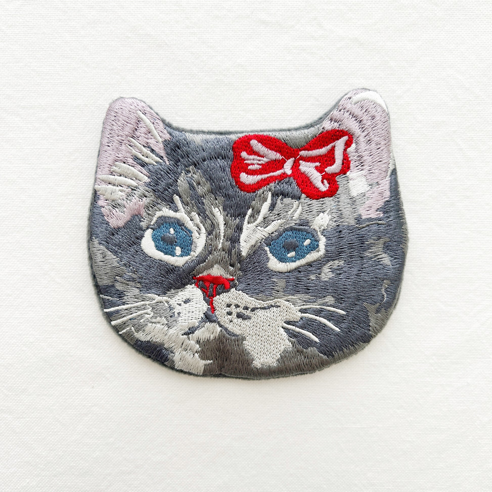 Embroidered pouch of a cat's face with a red bow