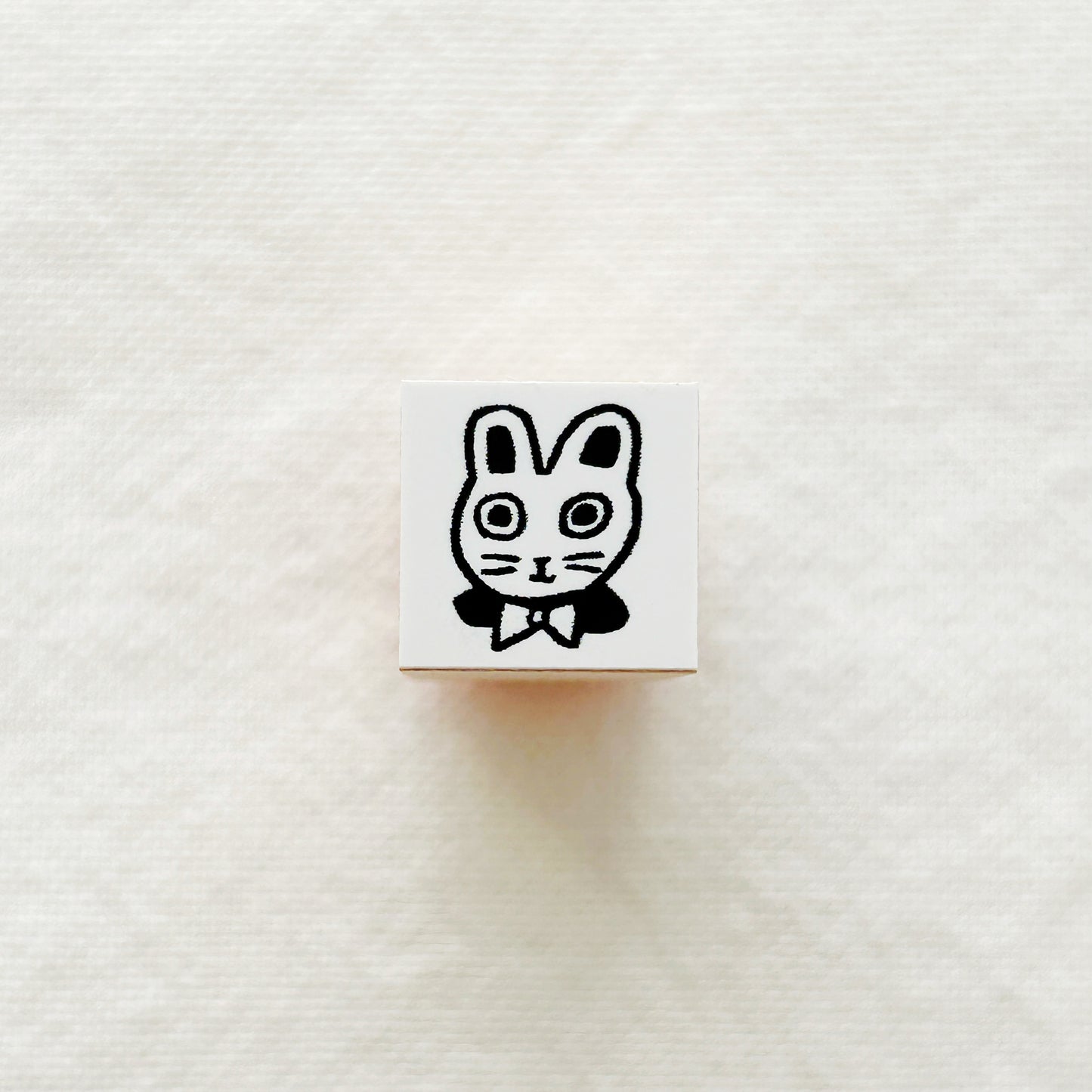 Small wooden rubber stamp with a black and white illustration of a bunny wearing a bow tie on a white background