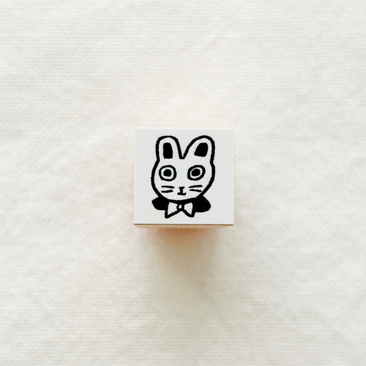 Small wooden rubber stamp with a black and white illustration of a bunny wearing a bow tie on a white background