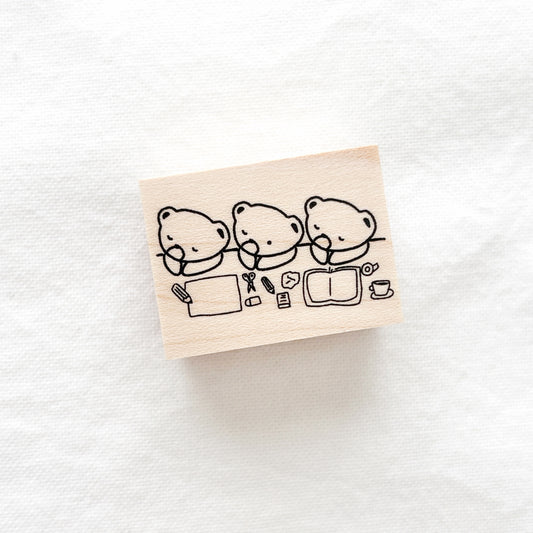 Wooden stamp with black illustrations of three bears working at a desk