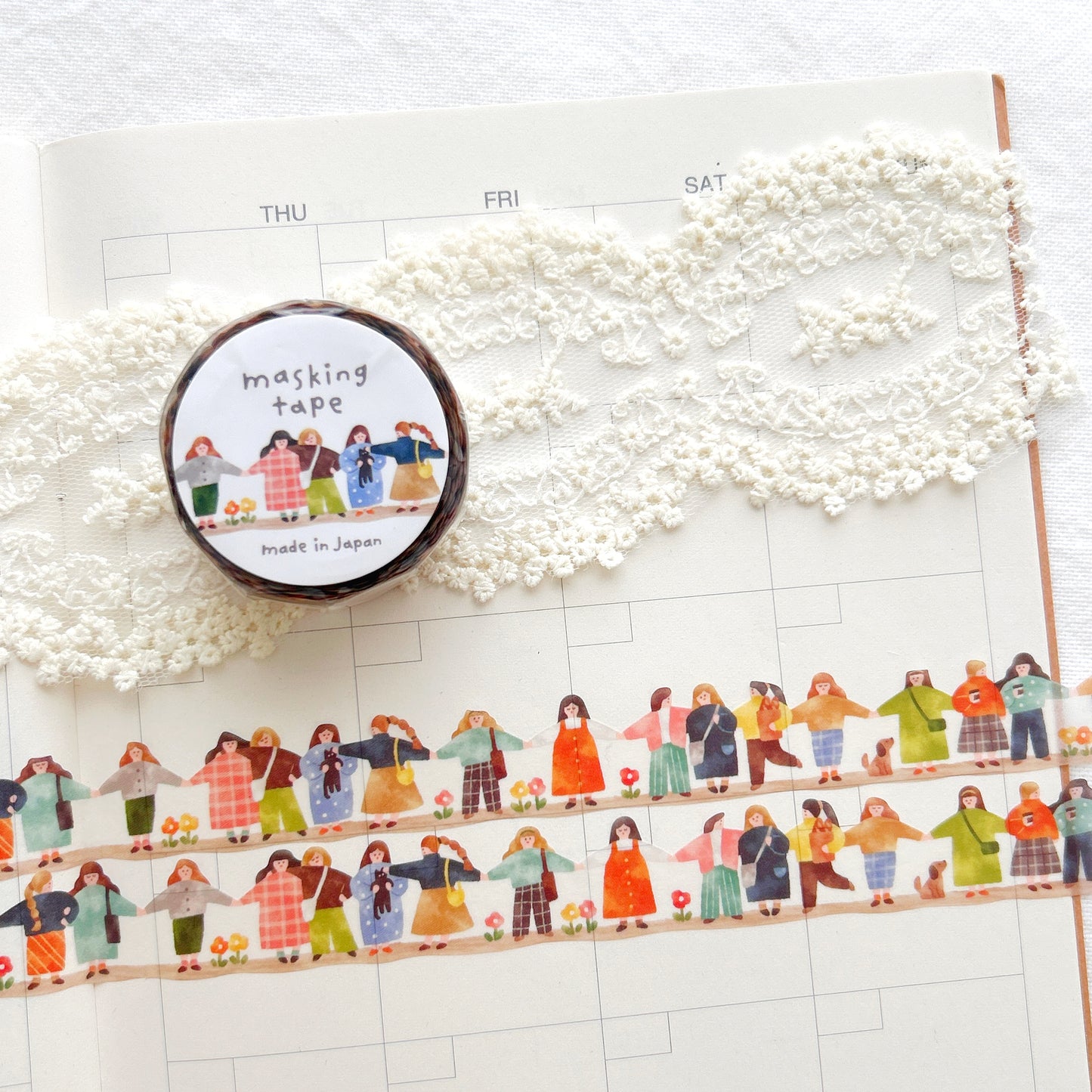 Decorative tape with colorful illustrations of people and a roll of washi tape on a journal