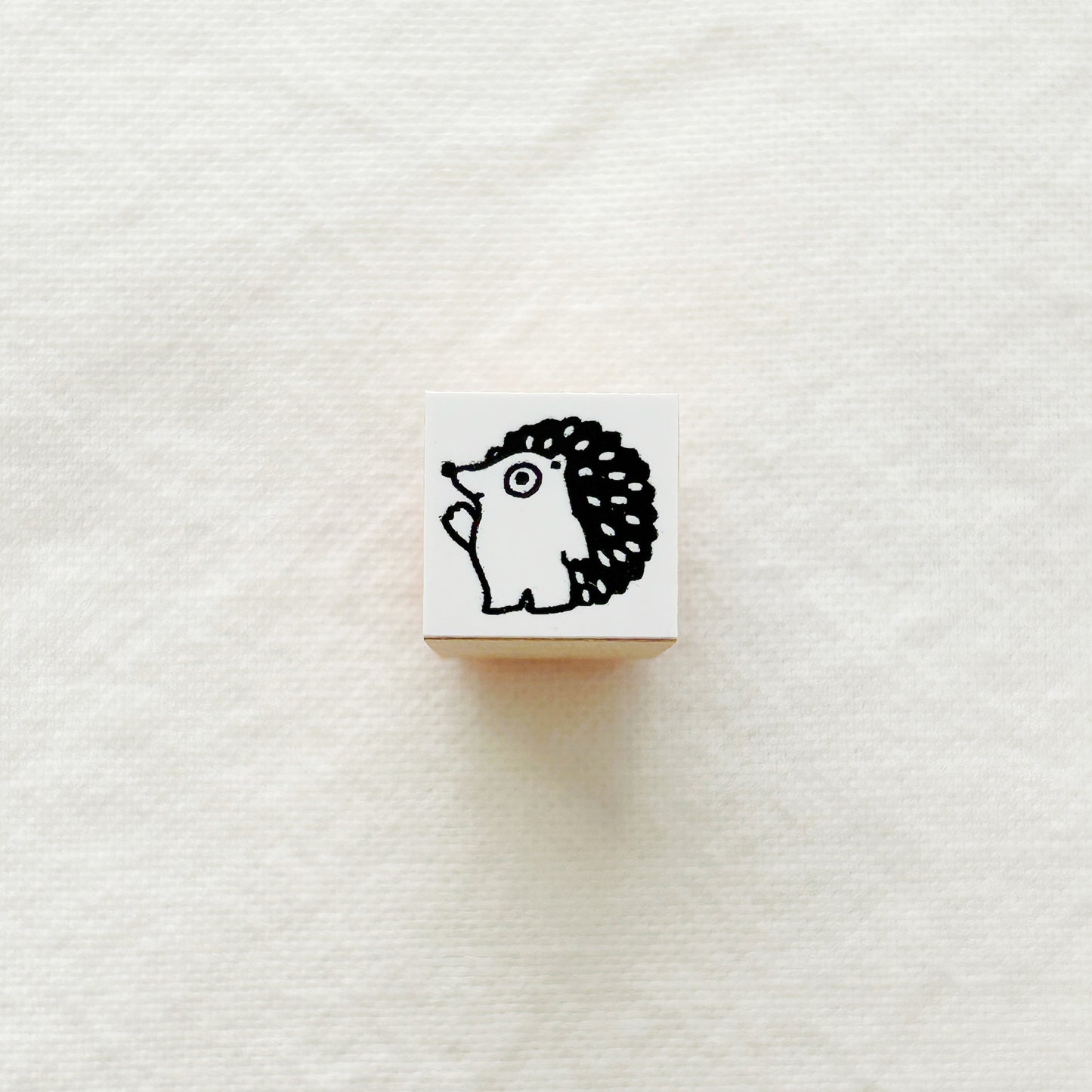 Small wooden rubber stamp with a black and white hedgehog .