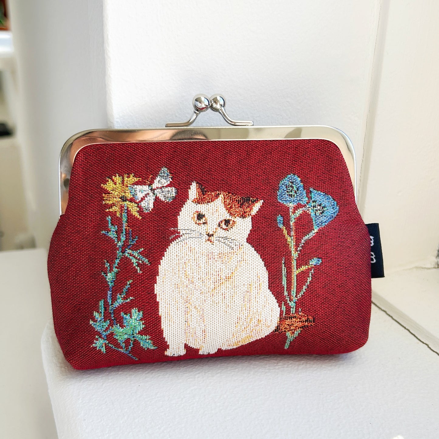 Embroidered purse with a cat design on a red background