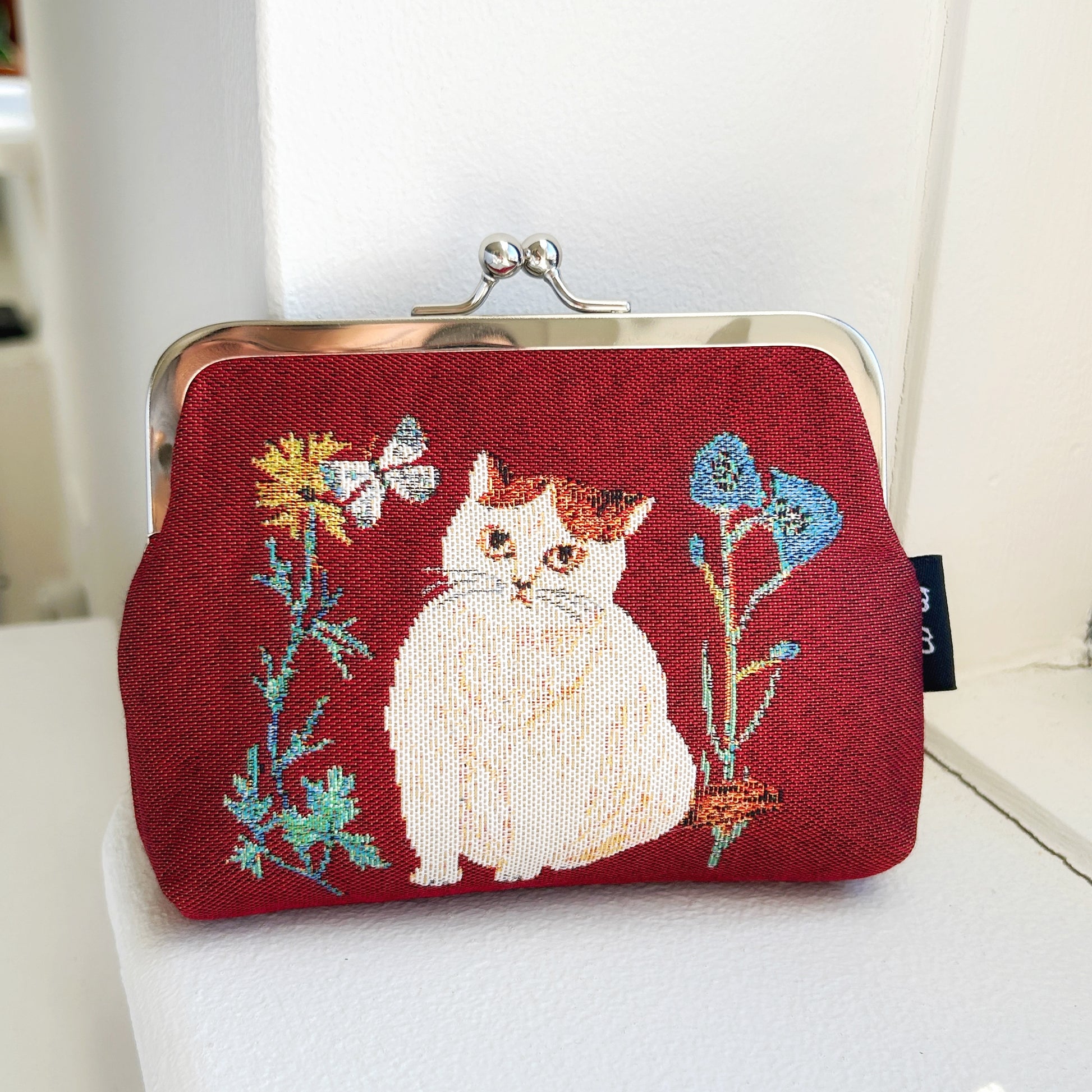 Embroidered purse with a cat design on a red background