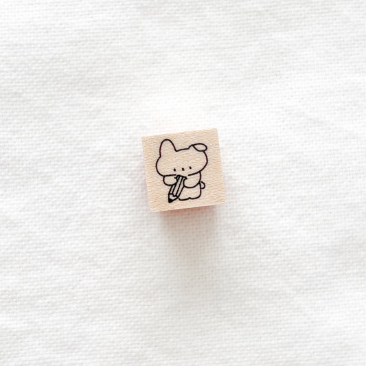Small wooden stamp with a bunny design holding a giant pencil