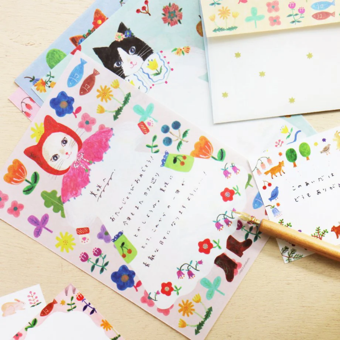 Aiko Fukawa letterhead featuring a cute cat and colorful floral design in a one-piece outfit, Japanese stationery with whimsical illustration style