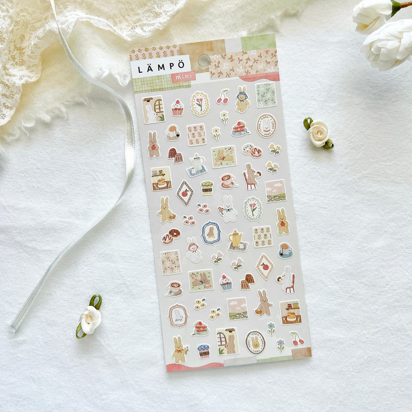 Sheet of decorative stickers with various cute designs of kawaii bunnies on a white surface with flowers.