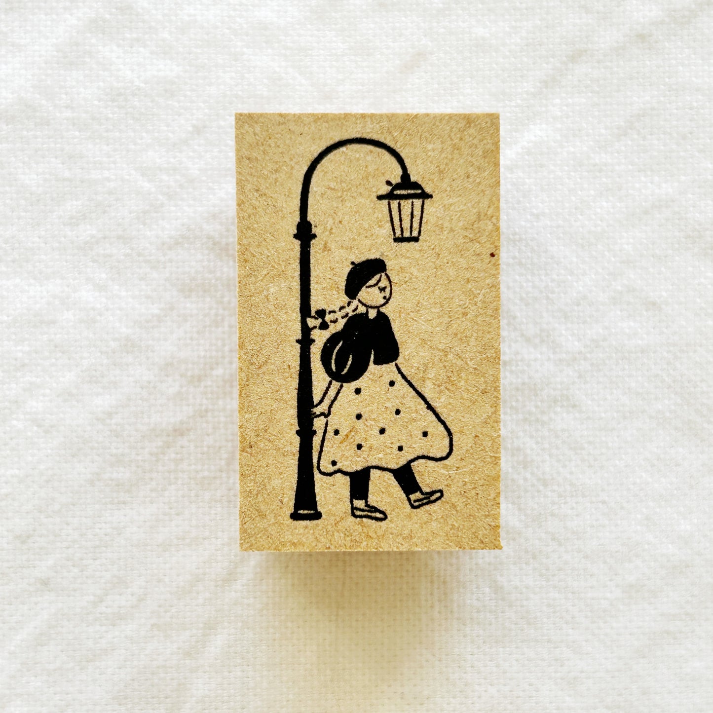 Wooden rubber stamp of a girl in a polka dot dress under a street lamp
