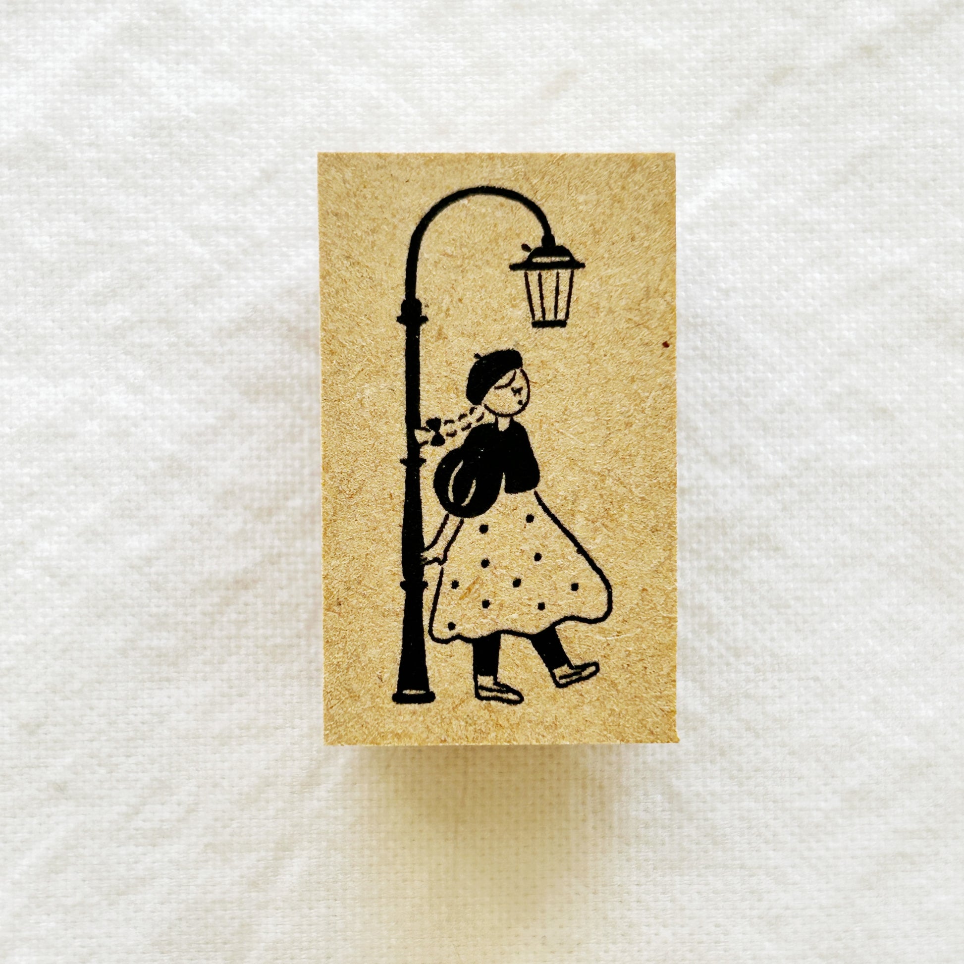 Wooden rubber stamp of a girl in a polka dot dress under a street lamp