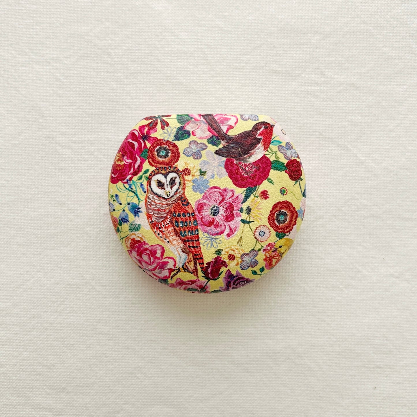 Round travel case a mirror including floral and owl design on a white background